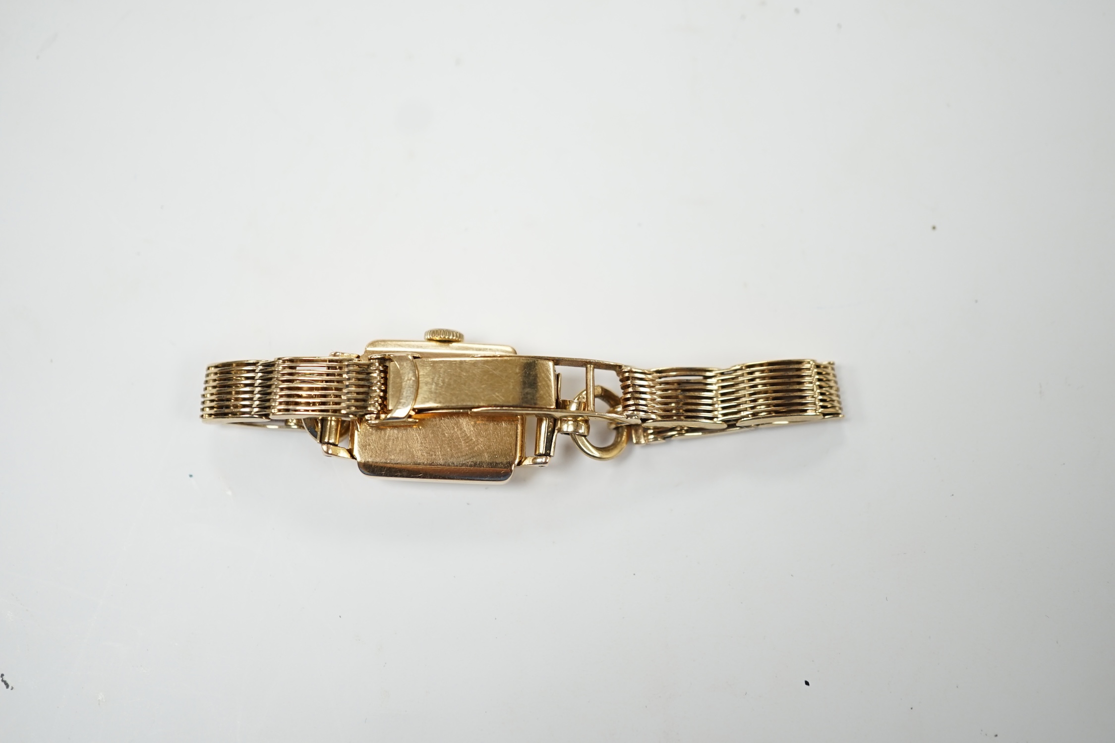 A lady's 18ct gold Movado manual wind wrist watch, on a 9ct gold bracelet. Fair condition